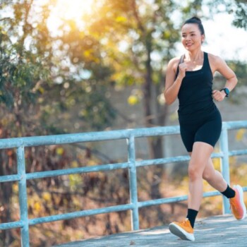 A woman in black workout attire jogging outdoors.