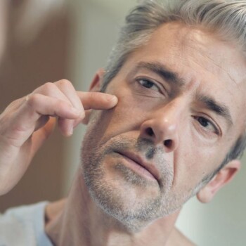 An older male touching his face examining his skin.
