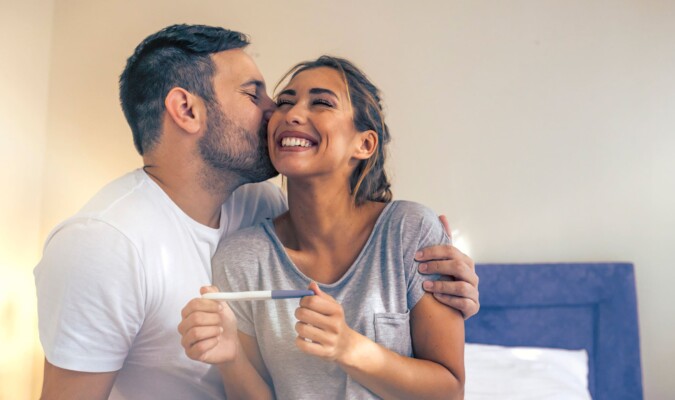 A smiling couple holding a pregnancy test.