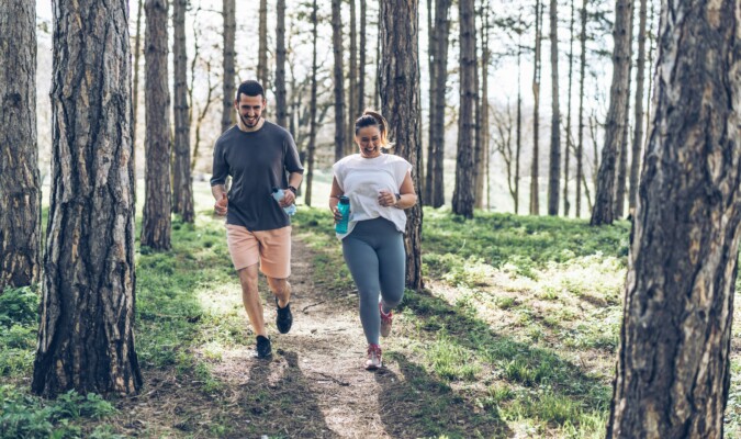 A man and woman jogging in the woods