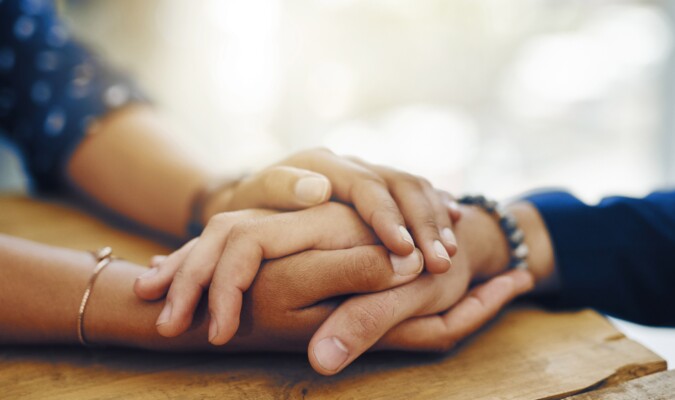 Someone holding a persons hands with both of theirs