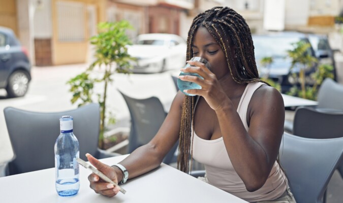 A woman looking at her phone while drinking water