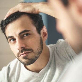 A man examining his hair in the mirror