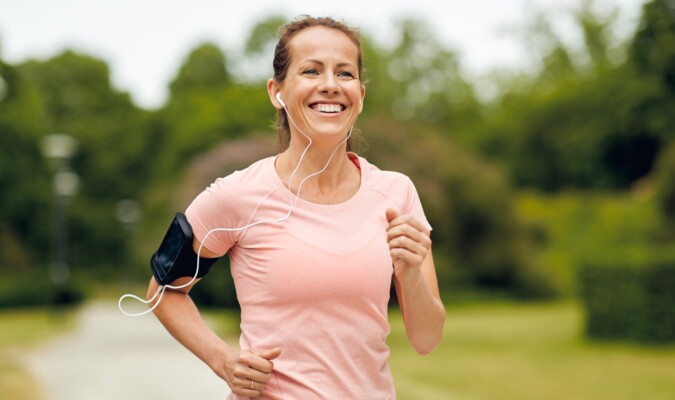 A woman in a light pink shirt running outdoors.