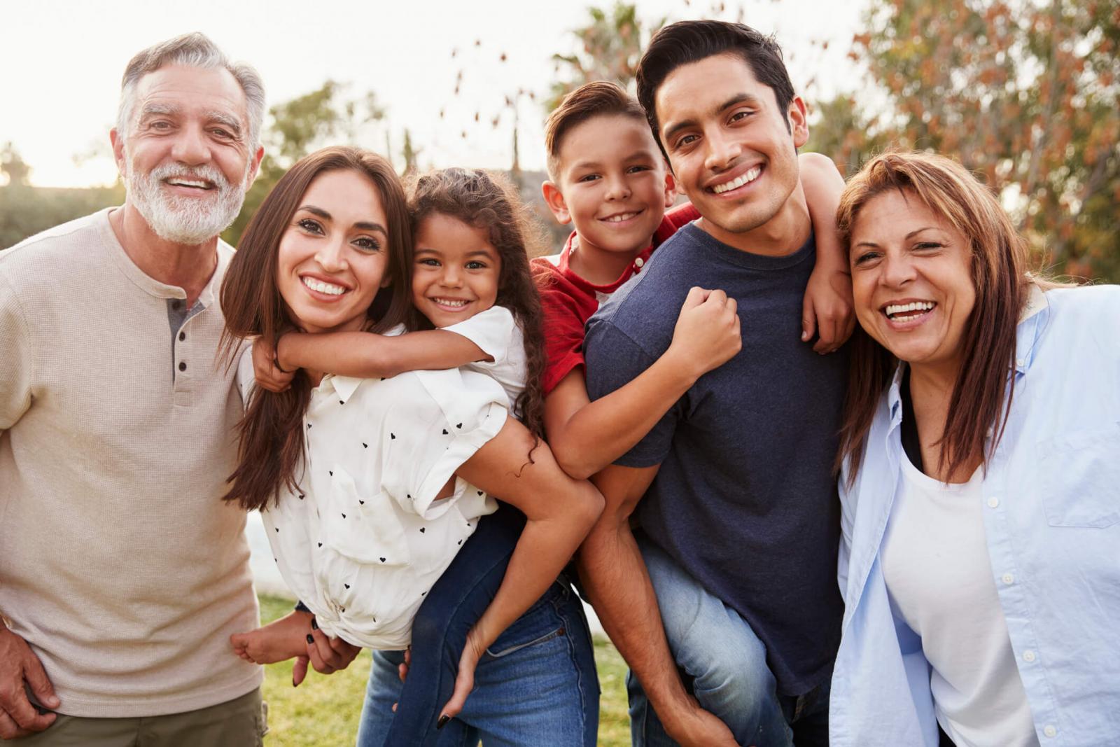 A family of six happy people in a field looking at the camera.