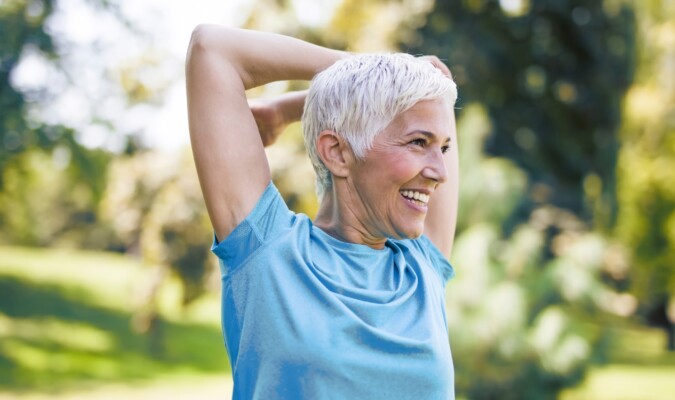 An older woman smiling and stretching.