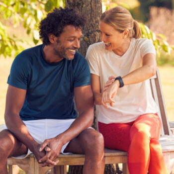Woman and man sitting on a bench while she touches her watch.