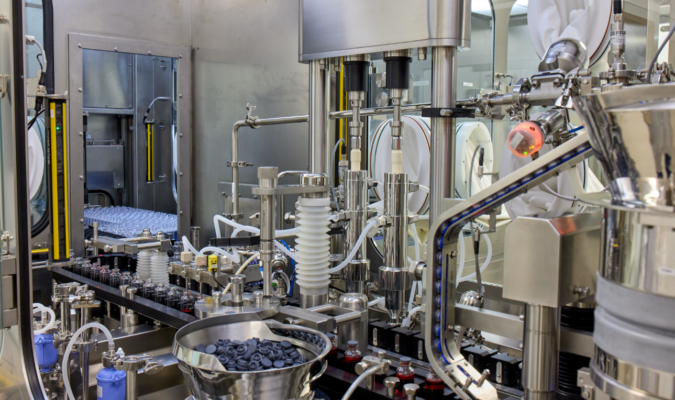 A machine that puts lids on full vials of liquid.