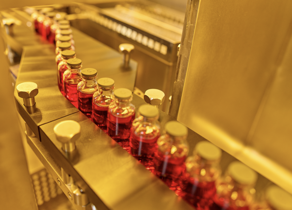 Vials of liquid entering a machine with an orange tint to the image.