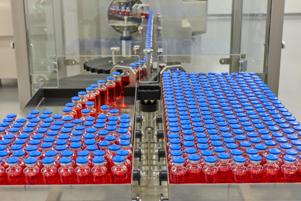 Vials of liquid being put onto a steel tray from a machine.