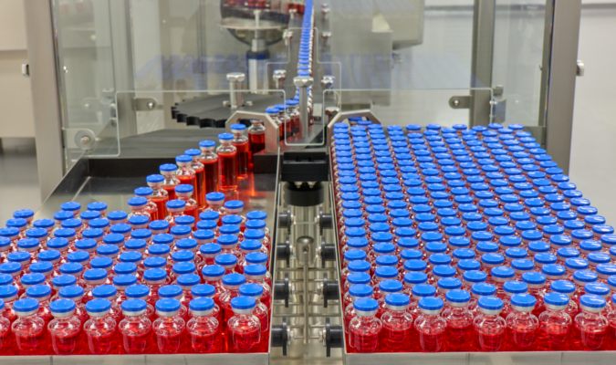 Vials of liquid being put onto a steel tray from a machine.