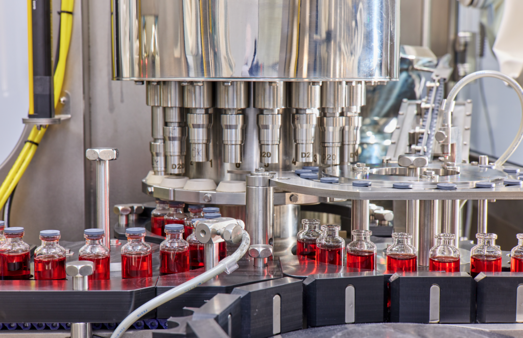 Vials of liquid getting lid put on in a machine.