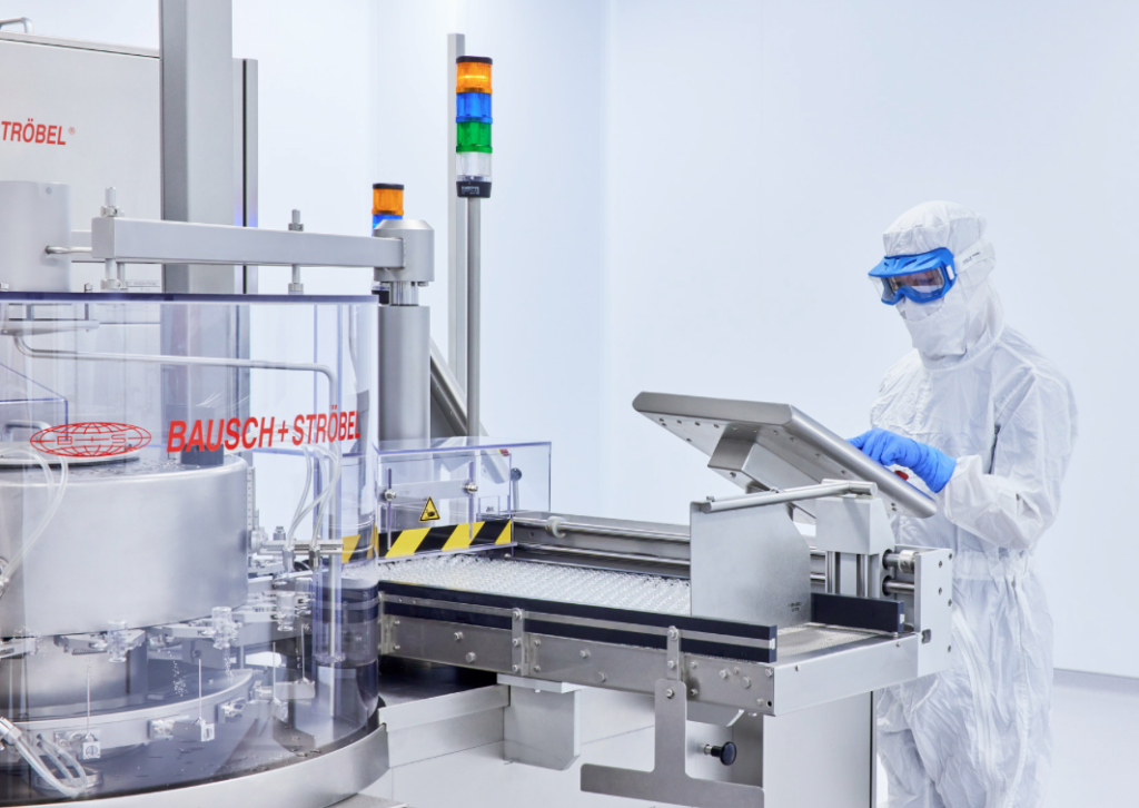 A worker in a white clean suit at a machine