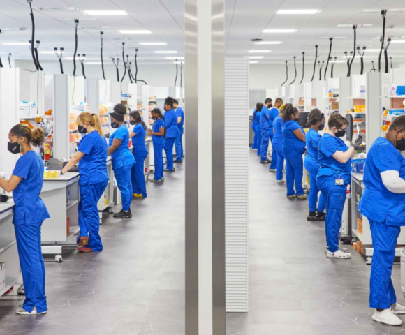 Two rows of workers in blue clean suits working at stations