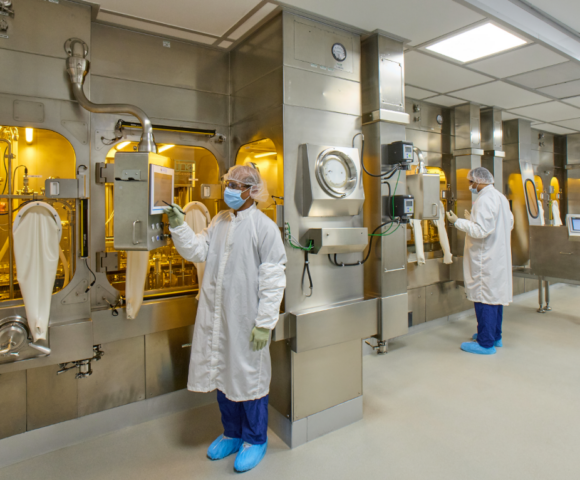A worker in a white clean suit working on a machine.