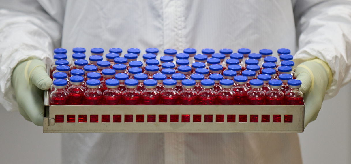 Someone holding a tray containing vials of liquid.