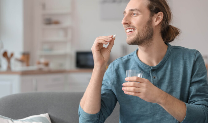 man taking pill with a glass of water