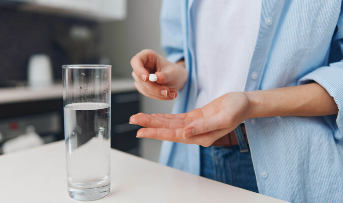 woman taking pill with a glass of water