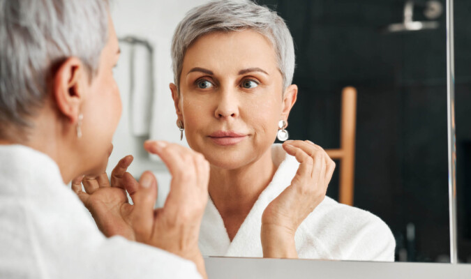 mature woman looking at face in mirror