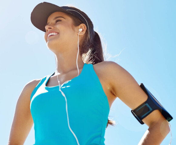 woman exercising outside wearing hat and listening to music